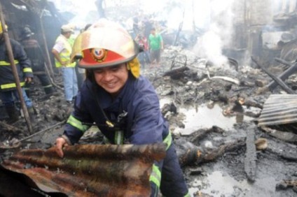 Bombeiro retira pedaço de teto de local onde avião caiu em favela de Manila, nas Filipinas, neste sábado (10) -
