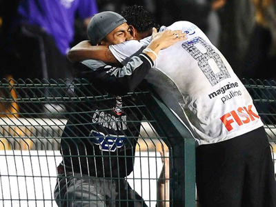 Paulinho comemora gol da vitória com torcedor no alambrado -