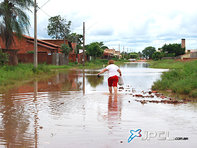 Com as águas na canela, dona Tânia atravessa a "Lagoa do Santo André" em direção à sua casa -