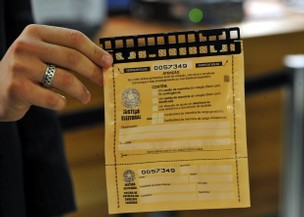 Servidor do Tribunal Superior Eleitoral (TSE) mostra envelope que teve seu lacre violado durante testes -