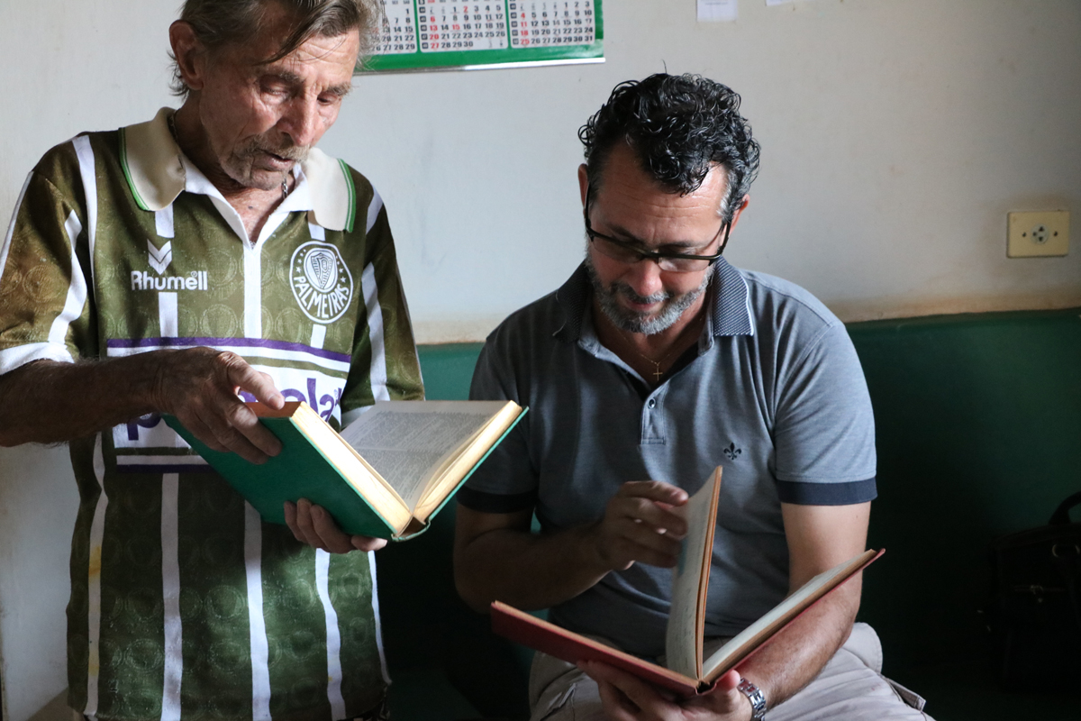 Idoso José Moreira (à esquerda) entrega livro para diretores de escolas - Divulgação/Assessoria