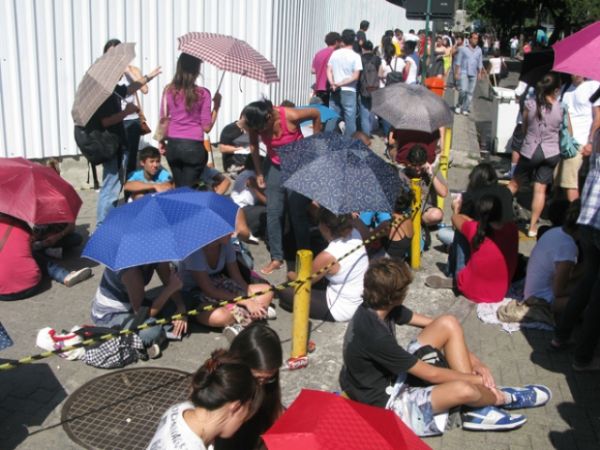 Em busca de ingressos para o Rock in Rio, pessoas usam guarda-chuvas para se protegerem do sol -