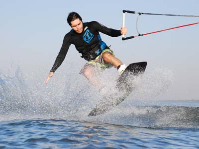 Atleta fica sobre uma prancha e é puxado por uma lancha no wakeboard -