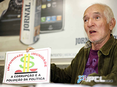 Miral segura um cartaz contra a corrupção durante a entrevista -