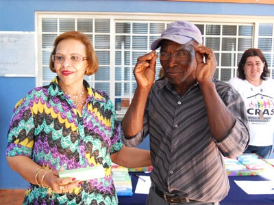 Secretária de Assistência Social, Maria Lúcia Firmino, entrega óculos a Alcides Simão do bairro São Carlos, assistido pelo CRAS São João -