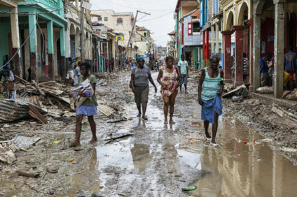 Mulheres caminham em rua alagada, com prédios destruídos, em cidade haitiana - Divulgação/ONU