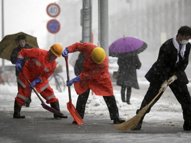Trabalhadores da estação ferroviária empurrar a neve da rua em Yokohama, Japão, sábado, 8 de fevereiro, 2014. - Arquivo/Radioshiga