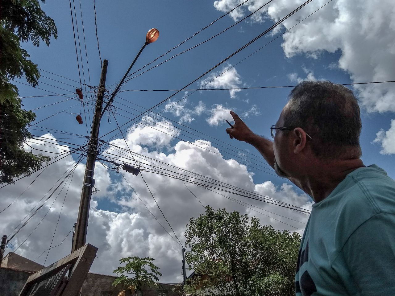 Morador mostra lâmpada acesa em poste de iluminação pública - Erick Marques/CBN CG