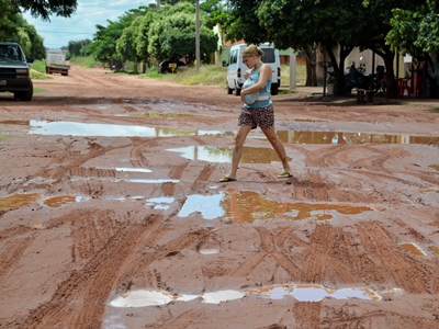 Em meio a poças d?água, moradora faz zigue-zague para atravessar a rua -