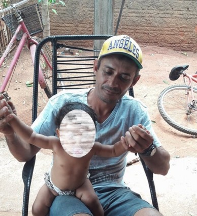 Gilberto, morto aos 41 anos, segura uma criança numa varanda - Álbum de família