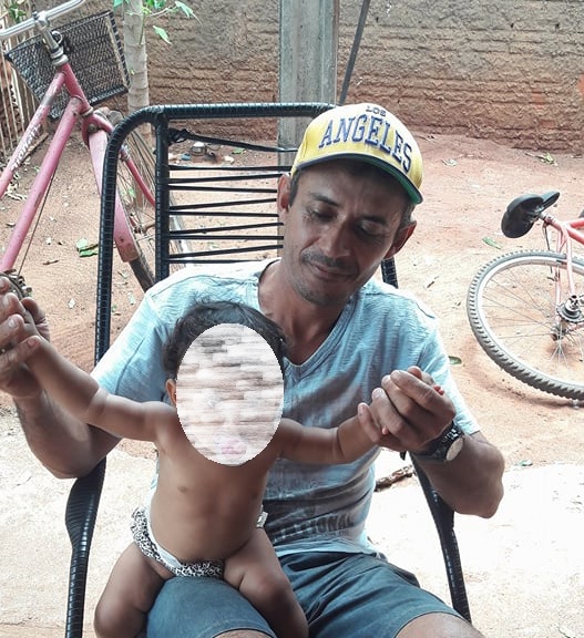 Gilberto, morto aos 41 anos, segura uma criança numa varanda - Álbum de família