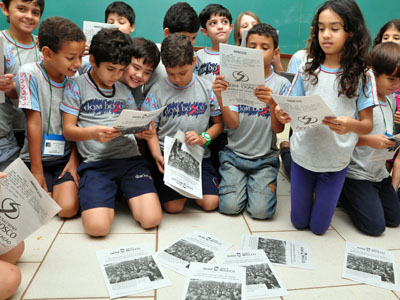 Alunos leem o próprio material impresso no jornal -