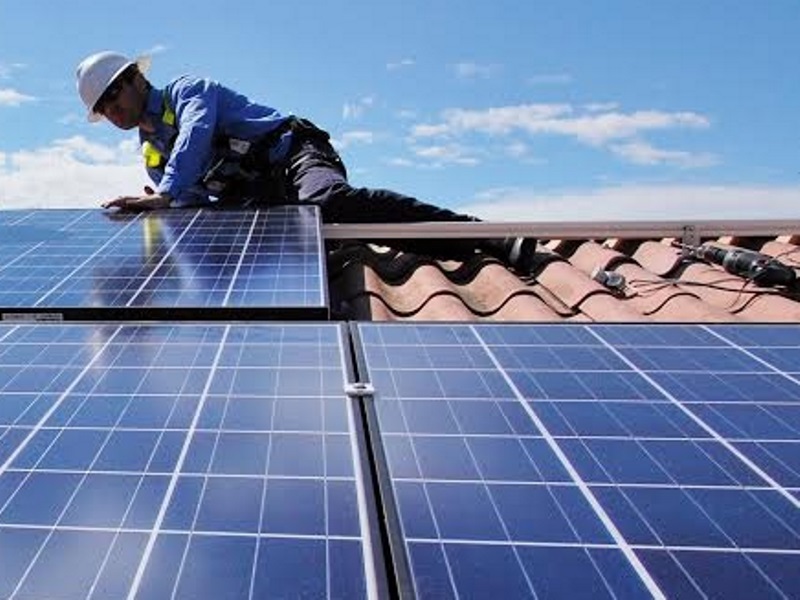 Técnico instala placas fotovoltaicas em telhado para alimentação de casa