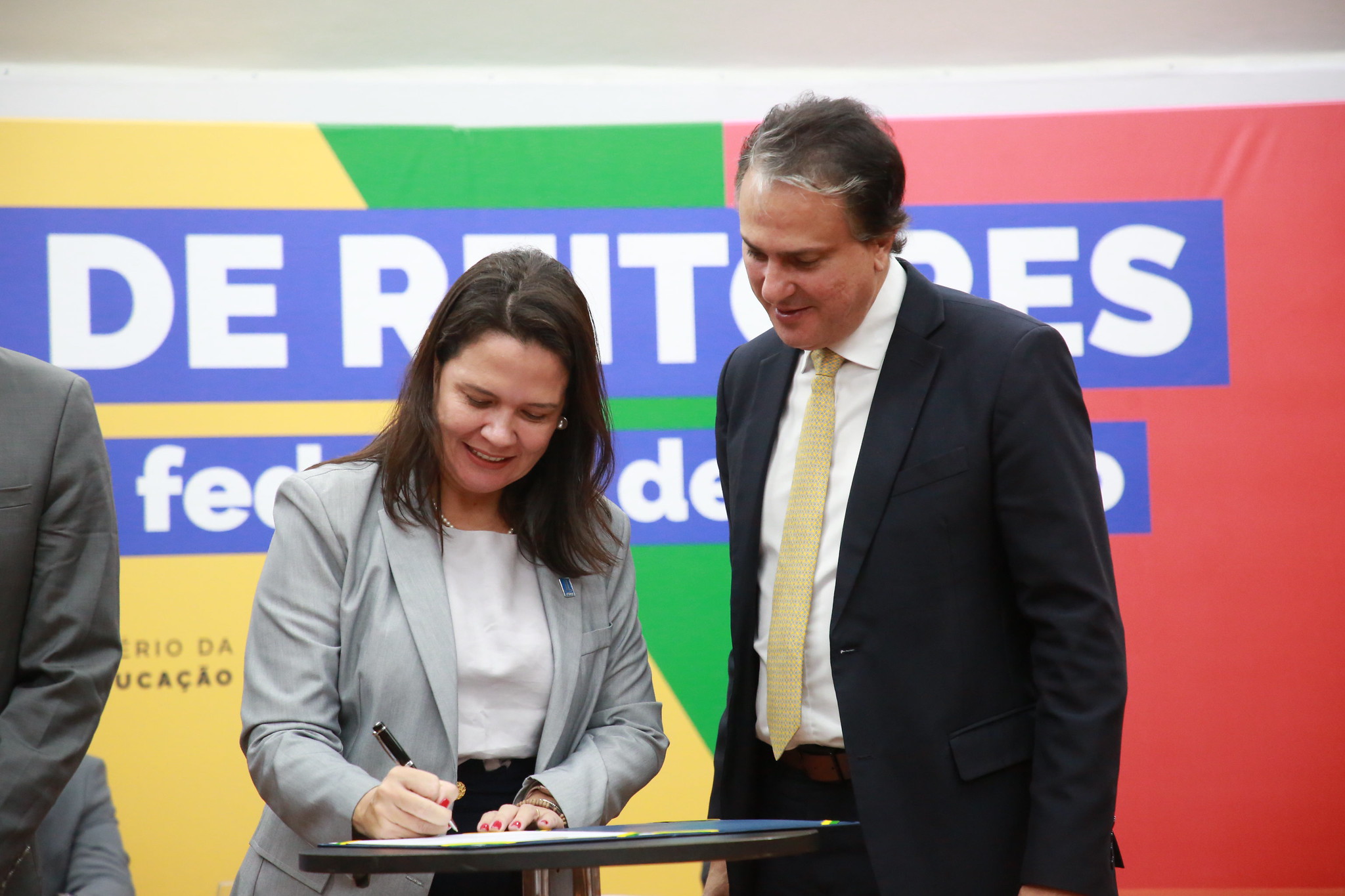 Camila ítavo assinando o termo de posse ao lado do Ministro da Educação, Camilo Santana