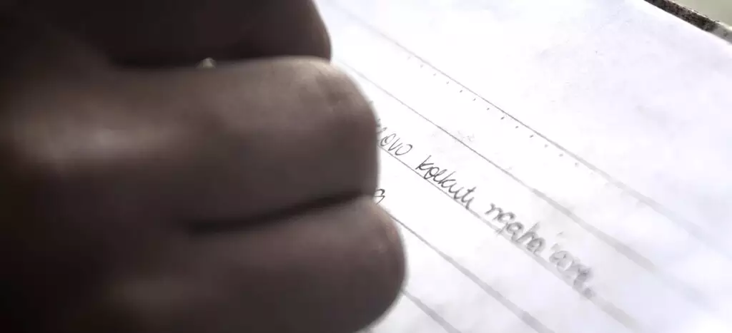 Indígena escreve em caderno na língua terena - Foto: Reprodução