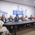 Vereadores e gestores da Sesau sentados em mesa de reunião na Câmara Municipal de Campo Grande, discutindo o abastecimento de medicamentos.