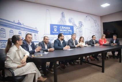 Vereadores e gestores da Sesau sentados em mesa de reunião na Câmara Municipal de Campo Grande, discutindo o abastecimento de medicamentos.