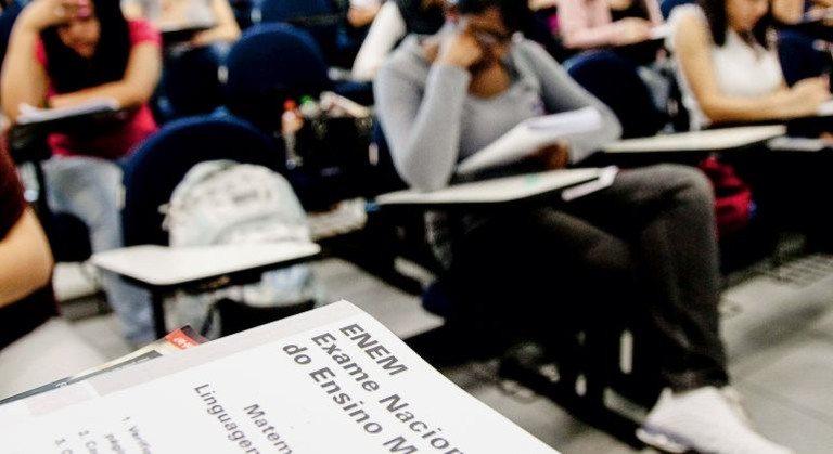 Estudantes consultando gabarito oficial do Enem em computador, com portal do Inep aberto