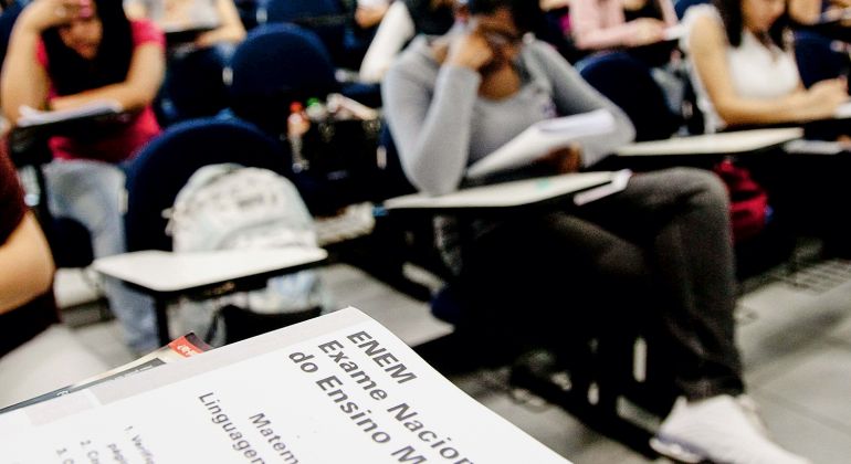 Estudantes consultando gabarito oficial do Enem em computador, com portal do Inep aberto