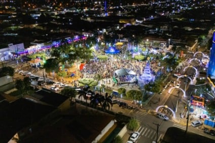 Papai Noel chegando em viatura do Corpo de Bombeiros na Praça Matriz lotada, cercado por famílias e crianças em noite de Natal