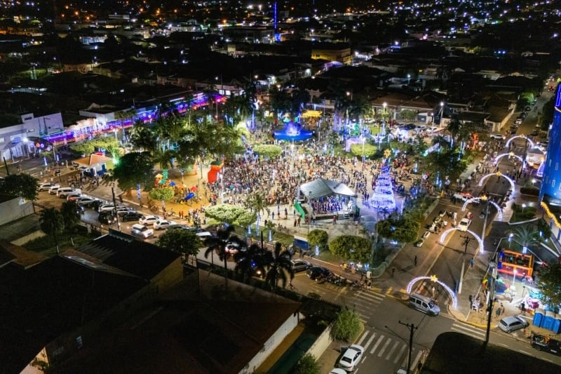 Papai Noel chegando em viatura do Corpo de Bombeiros na Praça Matriz lotada, cercado por famílias e crianças em noite de Natal