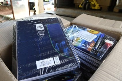 Caixas de kits escolares e materiais didáticos organizados para distribuição em escola pública de MS