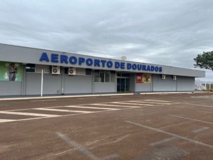 Engenheiros e arquiteto analisando planta de terminal de passageiros em área de obras de aeroporto regional