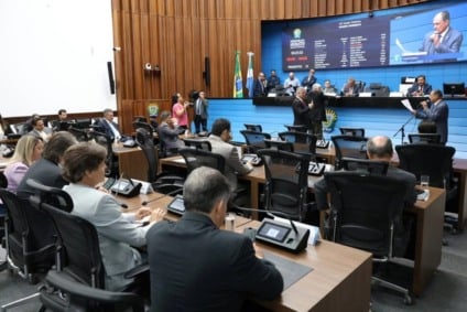 Paisagem aérea de rio de águas claras cercado por mata e áreas abertas de lavoura ao fundo, sugerindo contraste entre turismo e produção agrícola