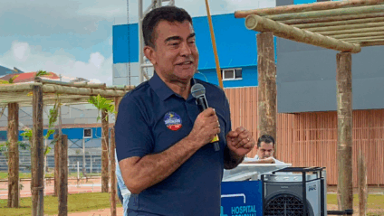 Cerimônia de entrega de hospital com autoridades desfocadas e fachada moderna ao fundo, em clima institucional