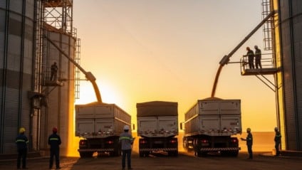 Carregamento de milho em caminhão ao lado de armazéns em região rural de Mato Grosso do Sul, com céu limpo e silos ao fundo