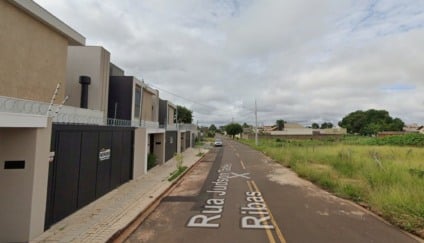 Viatura policial à noite em rua residencial com fita de isolamento e luzes refletindo, sem pessoas identificáveis