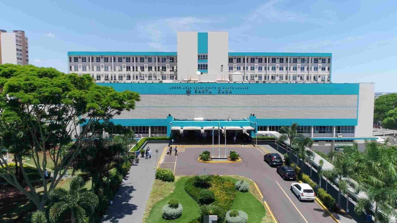 Fachada da Santa Casa de Campo Grande sob chuva, simbolizando crise e alívio temporário com acordo financeiro Fachada da Santa Casa de Campo Grande sob chuva, simbolizando crise e alívio temporário com acordo financeiro