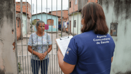 Agentes comunitários de saúde em atividade e documentos de empenho sobre mesa, em cenário institucional