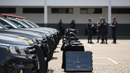 Viaturas policiais novas alinhadas em pátio oficial, com agentes ao fundo e clima de reforço operacional em MS.