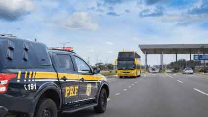 Ônibus intermunicipal em rodoviária com aviso de novas linhas e fiscalização